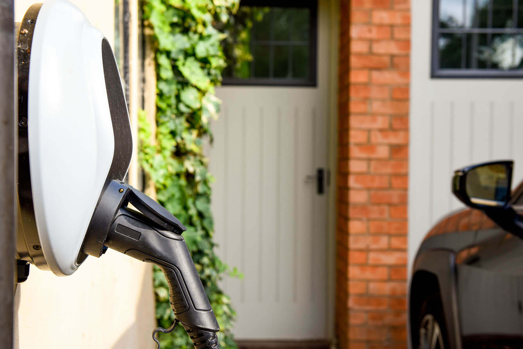 Home EV charging station mounted beside a garage with car plugged in