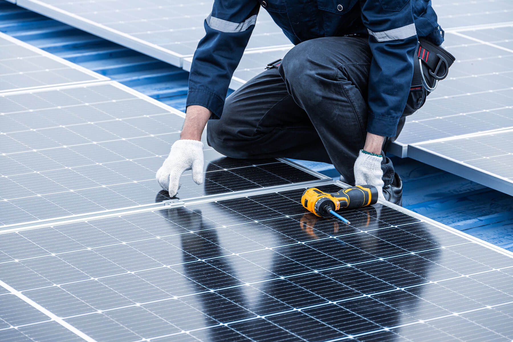 MCS-certified installer hand-fitting a solar panel onto rooftop mounting rails